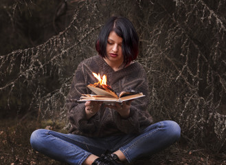 the book burns in the hands of a woman - obrazy, fototapety, plakaty