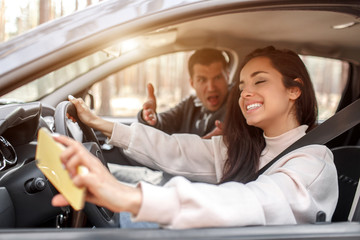 Driving instruction. A young woman learns to drive a car . Her instructor or boyfriend doesn't like the way she drives a car. But the girl is pleased with herself and does not listen to the guy.