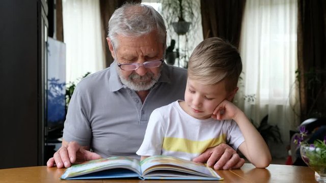 Grandfather senior man reading a book with his grandson