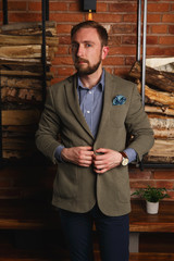 Side view of young fashion man in stylith blaizer standing in modern loft interior