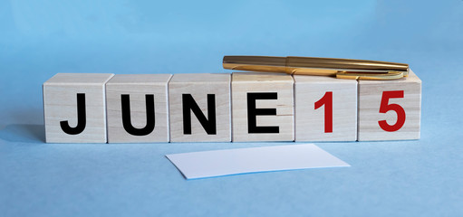 June 15 tax Date Cube blocks with pen and paper cards on blue Background. Tax date concept
