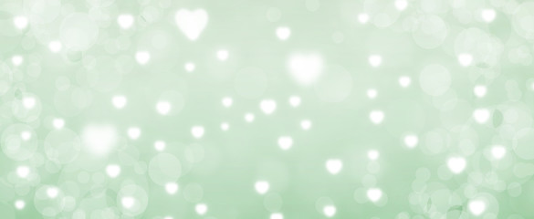 Glowing green bokeh background. Spring concept. Blurred bokeh circles and hearth shapes.  Website banner. Celebration.  Christmas.