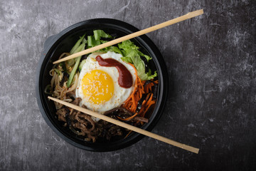 Korean dish bibimbap. Top view close up. Nearby are the Korean sticks.