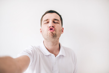 Obraz premium Young man isolated over white background. Ridiculous guy hold lips together like duck. Kissing mode. Funny posing on camera. Hold it with hand.