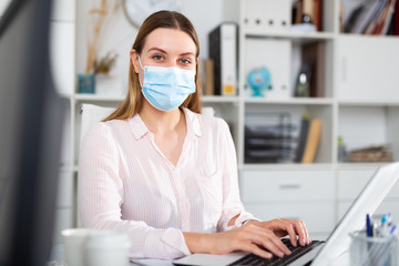 Fototapeta na wymiar Woman in protective face mask working at office