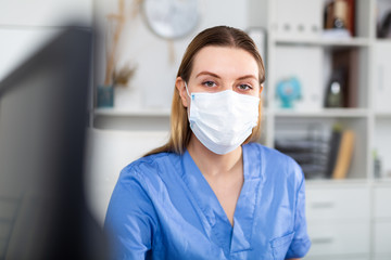 Woman doctor in face mask working on laptop