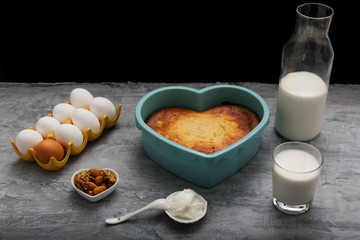 heart-shaped casserole and ingredients on a dark background 