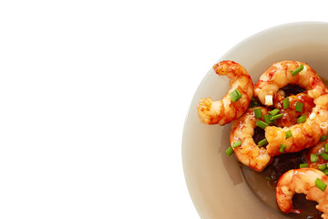 Large pacific prawns in sweet and sour sauce with chopped green onions on a glass transparent plate. Isolate, white background, for the menu.