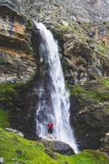 Obraz premium Man under a spectacular waterfall in the mountains