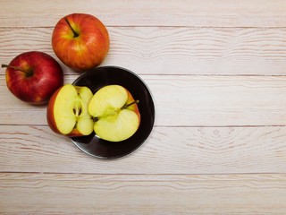 light background with red apples, fruits on a black plate