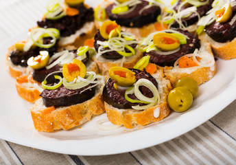 Dish of canape from blood sausage with  olives, onion and bread