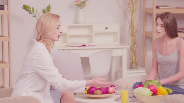 Nutritionist explains to client example of beneficial properties of generalities. Girl at consultation with nutritionist who tells her benefits of proper nutrition. Tone video. Prores 422