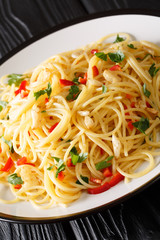 Spaghetti Aglio e Olio is a simple Italian dish of garlic, olive oil, parsley close-up in a plate on the table. Vertical