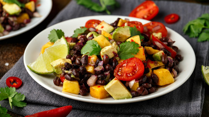 Avocado, mango salad with black bean on white plate