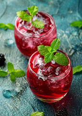 Refreshing Blackberry cocktail with ice and mint on rustic background