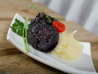 Tasty blood sausage with mashed potato and greens served at plate