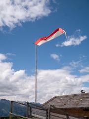 Flag of tyrol flying on an alpine hut in the wind with a cloudy sky in South Tyrol, North Italy.