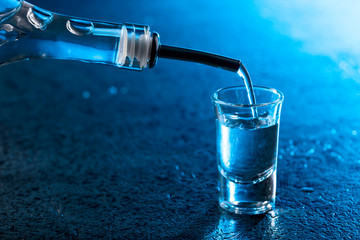 Vodka poured into a glass lit with blue backlight.