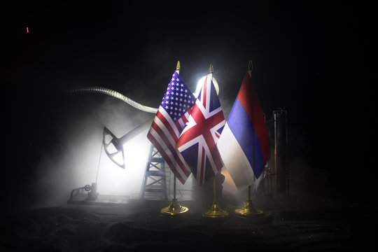 Business dialogue, oil agreement concept: National flags with Oil pump and oil refining factory at night with fog and backlight. Energy industrial concept.