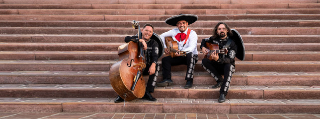 Mexican musicians play musical instruments in the city. City street in the summer.