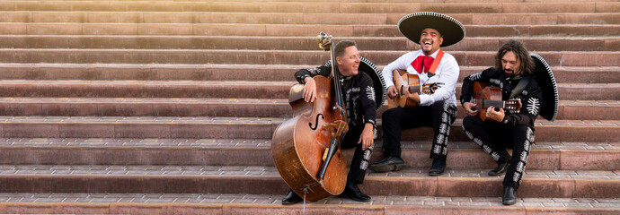 Mexican musicians play musical instruments in the city. City street in the summer.