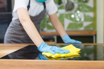 Unrecognizable young woman disinfecting kitchen counter with microfiber