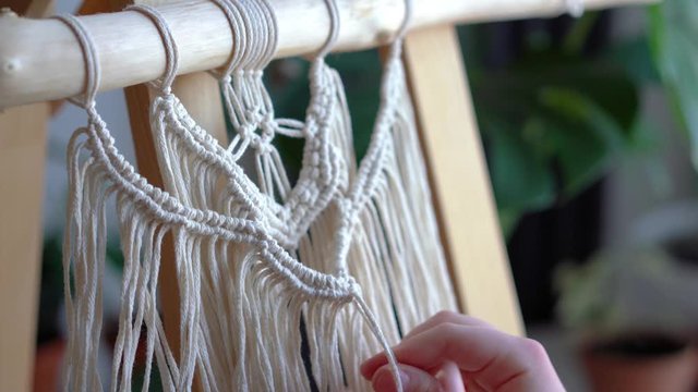 stay at home. work during the quarantine - a girl in the living room mural weaving of the ropes in the macrame technique