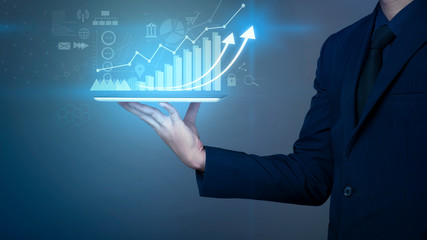 Businessman is holding financial growth graph and analyzing business data, business plan and strategy concept .