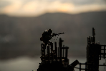 Army sniper with large caliber rifle standing in the fire and smoke. War Concept. Battle scene on...