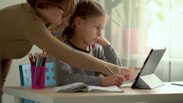 Homeschooling for children. Son and daughter use a laptop for education. Mom helps with homework. Stay home concept.