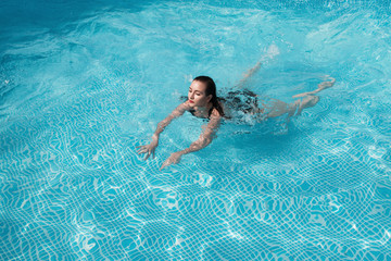 fashion photo of a sexy beautiful girl in elegant bikini posing and takes a sunbath in the swimming...