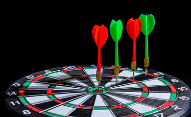 Red and green dart arrow hitting target center is Dart board Isolated on black background