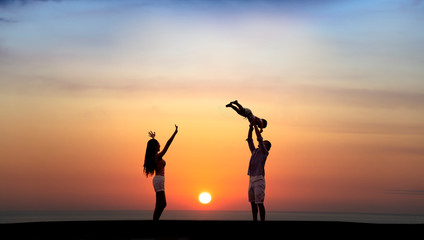 happy family playing on the beach at sunset