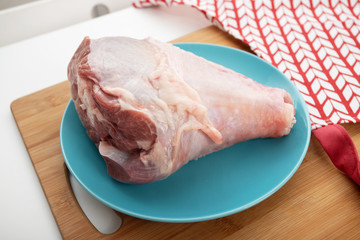 Dietary meat. Raw turkey leg unprepared on a table on a blue plate