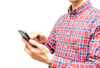 Young man in a plaid shirt with a smartphone on a white background. The guy looks at the camera and holds a smartphone in front of him and points, presses a finger into  it
