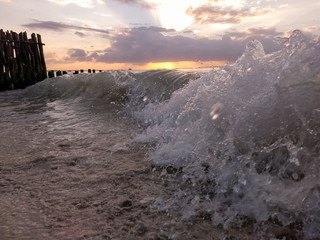 The crest of a wave from very close, with a beautiful sunset in the background