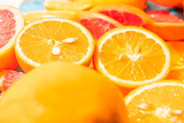 Close up of two pieces sliced round oranges in between many other fresh citrus fruits with shallow depth of field