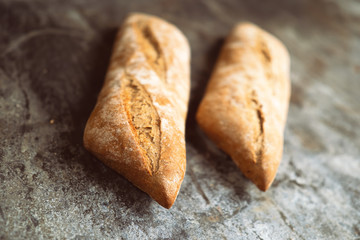 Fresh bakery food. Crusty loaves of baguettes on rustic table background. Shallow DOF and copy space for your advertising text message or promotional content