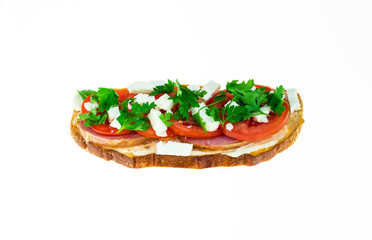 Toast with feta cheese, tartar sauce, parsley greens, tomatoes and smoked meat on dark grain bread on white isolated background.