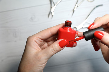 Naklejka premium Selfmade manicure service. Manicurist paints nails with red gel polish. Nail polish application. Manicured nails.