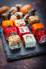 Assorted rolls and sushi on a stone plate, side view.