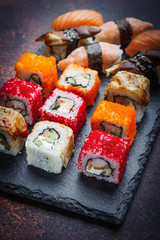 Assorted rolls and sushi on a stone plate, side view.
