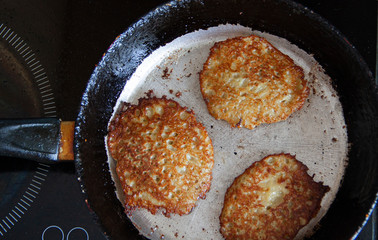 Potato pancakes are fried in a hot pan. Pancakes.Top view 