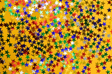 Multicolored bright shiny stars on a yellow background. Star background.