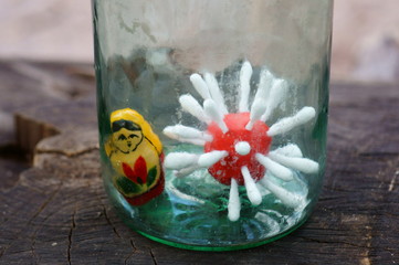 A virus figurine made of plasticine and a small nesting doll in a glass jar.