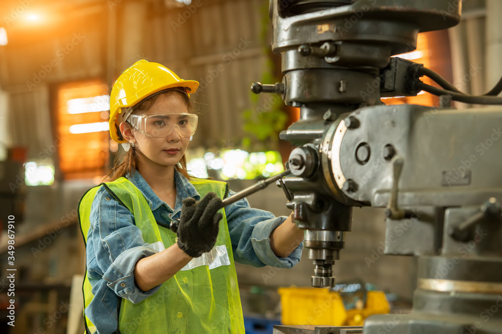 Poster female technician worker working and checking machine in a large industrial factory.