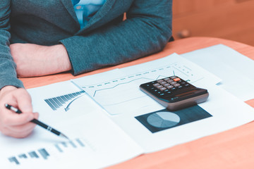 Side view of Cropped picture businessman working on desk office  financial graph with using a calculator to calculate the numbers,accounting investment and finance concept.