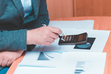 Side view of Cropped picture businessman working on desk office  financial graph with using a calculator to calculate the numbers,accounting investment and finance concept.