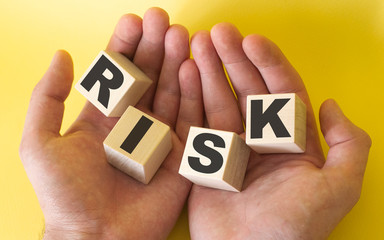 Closeup male hand with wooden blocks Risk text Risk management concept.