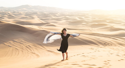 Happy girl dancing in the desert. A woman enjoys a vacation and a journey through the desert.
